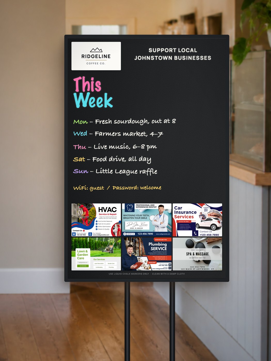 A Community Board on its stand inside a coffee shop, showing the host logo, the week&rsquo;s handwritten notes and six business placements